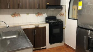 A compact kitchen with dark wooden cabinets, a gas stove, a sink, and a refrigerator. - Joint apartments near Bello Ant’s Town Square (Bello)