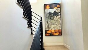 A wooden staircase with a black railing and a modern abstract painting on the wall. - Stylish 2BR Suite in Vibrant LA Area -> Complimentary WiFi, AC & Parking (Los Angeles)