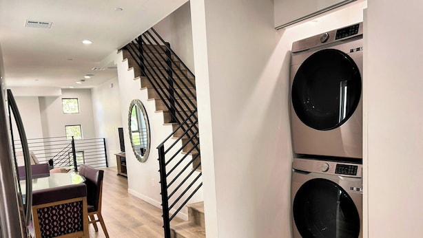 A modern kitchen with a built-in washer and dryer, a wooden staircase, and a dining area with a table and chairs. - Stylish 2BR Suite in Vibrant LA Area -> Complimentary WiFi, AC & Parking (Los Angeles)