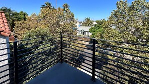 A balcony with a metal railing overlooking a residential area with houses and palm trees. - Stylish 2BR Suite in Vibrant LA Area -> Complimentary WiFi, AC & Parking (Los Angeles)