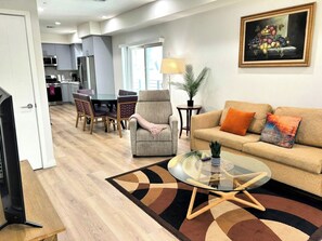 A modern living room with a sofa, armchair, coffee table, and dining area with chairs and a table. - Stylish 2BR Suite in Vibrant LA Area -> Complimentary WiFi, AC & Parking (Los Angeles)