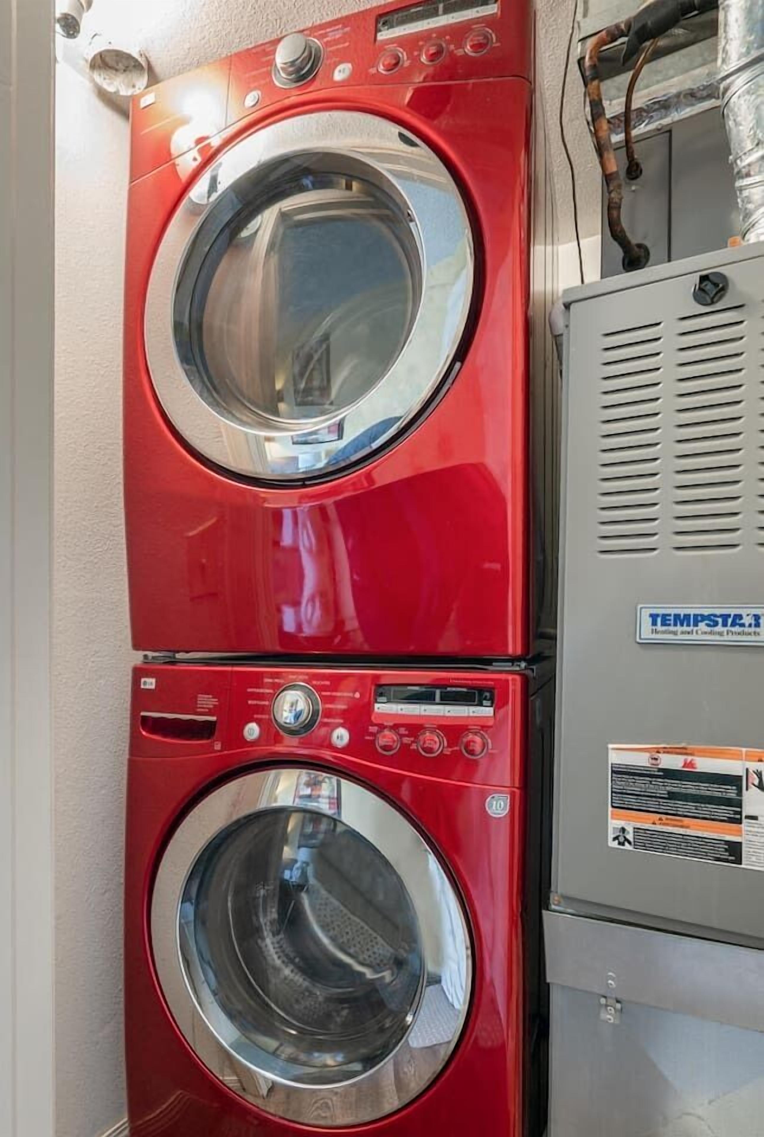 A red wall-mounted washer and dryer unit with a control panel and a temperature control box.