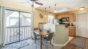 Une cuisine moderne avec des meubles en bois, un îlot central et un coin repas comprenant une table et des chaises.