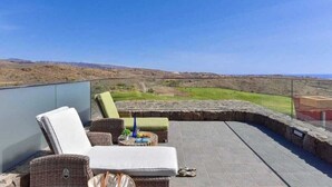 Una terraza con mobiliario de mimbre y vista a un paisaje montañoso.