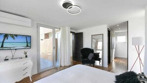 Un dormitorio moderno con una cama grande, un televisor montado en la pared, un aparador y una silla.