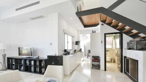 Una sala de estar moderna con televisión, estanterías y chimenea.
