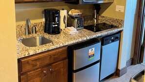 A kitchen with wooden cabinets, a stainless steel microwave, a coffee maker, a toaster, and a dishwasher.