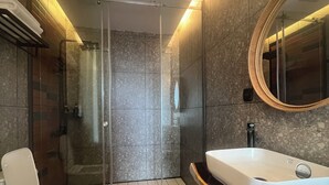 Un baño moderno con cabina de ducha de vidrio, inodoro blanco y un espejo grande.