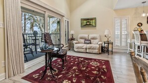 A spacious living room with a large window, a sofa, a coffee table, and a fireplace. - 3 Miles from beach. 2-bedroom, 2 bath condo in Little River with 3 beds. (Little River)