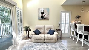 A living room with a beige sofa, a patterned rug, a dining area with white chairs, and a painting on the wall. - 3 Miles from beach. 2-bedroom, 2 bath condo in Little River with 3 beds. (Little River)