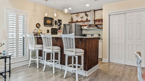 A kitchen with a central island, white bar stools, pendant lighting, and a refrigerator. - 3 Miles from beach. 2-bedroom, 2 bath condo in Little River with 3 beds. (Little River)