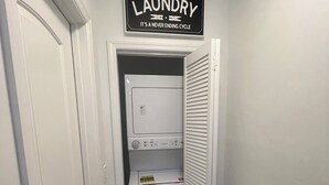 A laundry room with a sign above a stacked washer and dryer. - Fun in the South and Sun (Hallandale Beach)