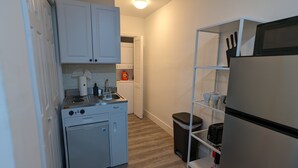 A compact kitchen with white cabinets, a built-in stove, a sink, and a small refrigerator. - Fun in the South and Sun (Hallandale Beach)