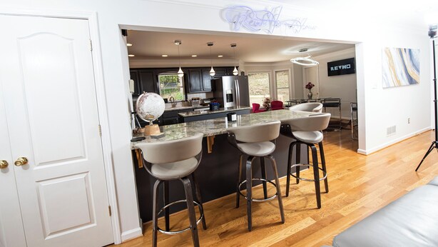 Une cuisine moderne dotée d’un îlot central, de tabourets de bar et d’un panneau lumineux au néon.