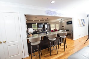 Una cocina moderna con una isla central, taburetes de bar y un letrero de neón.