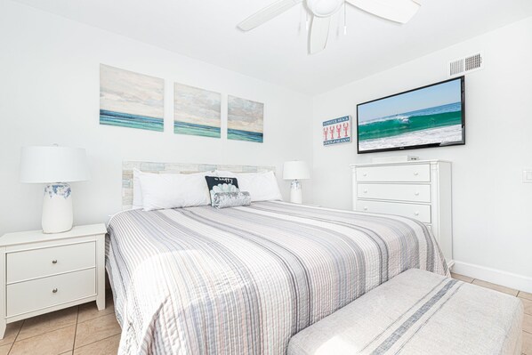 A bedroom with a bed, two bedside tables, a nightstand, a dresser, and a ceiling fan.