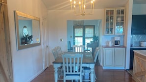 A spacious dining area with a wooden table and chairs, a chandelier, and a view into the kitchen. - The Ark!!! (Sulphur Rock)