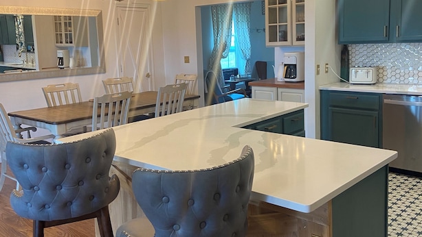 A modern kitchen with a central island, bar stools, pendant lighting, and a view into the dining area. - The Ark!!! (Sulphur Rock)