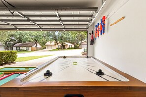 Una mesa de fútbol en un garaje con vista a una calle residencial.