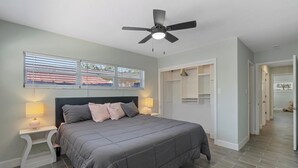 A bedroom with a bed, nightstands, a ceiling fan, and a window with blinds.