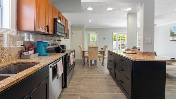 A modern kitchen with granite countertops, wooden cabinets, and a central island.