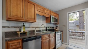 A kitchen with wooden cabinets, a stainless steel dishwasher, an oven, a microwave, and a sink.