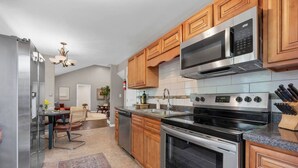 A modern kitchen with stainless steel appliances, wooden cabinets, and a granite countertop.