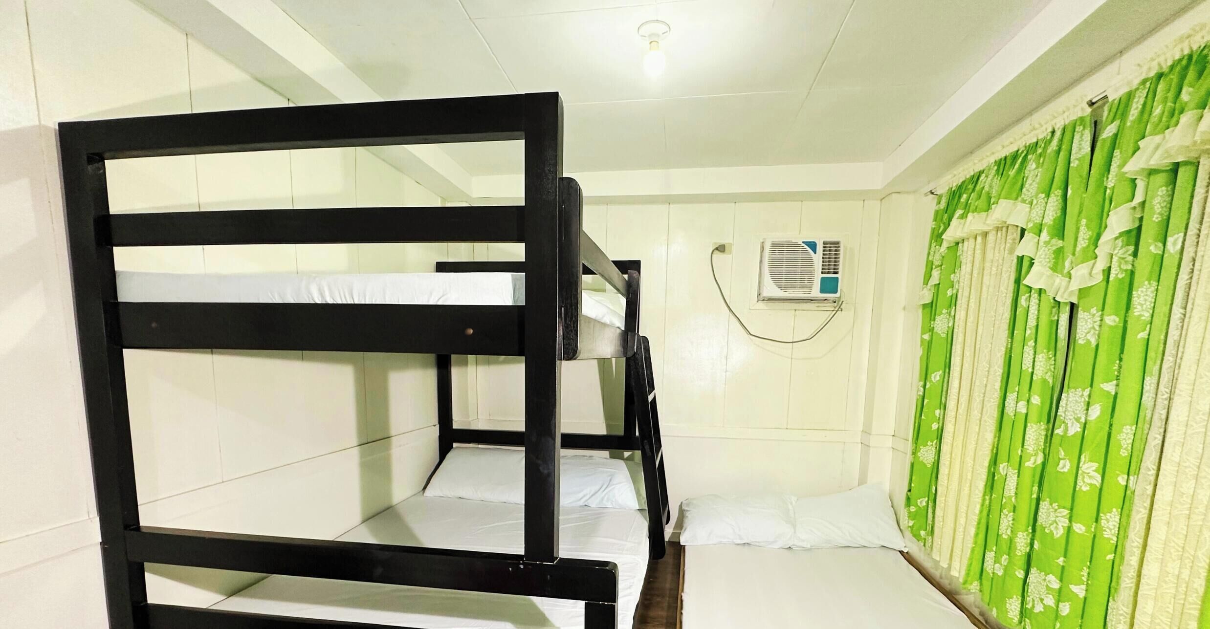 A bunk bed room with white walls, a green curtain, and an air conditioning unit.