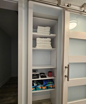 Un vestidor con repisas para toallas dobladas y un espacio para ropa doblada.