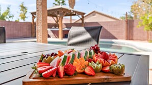 Une planche en bois sur laquelle sont disposés différents fruits coupés en tranches, avec une piscine en arrière-plan.