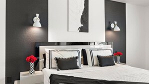 Une chambre moderne avec un grand lit, une décoration en noir et blanc et des œuvres d’art accrochées aux murs.