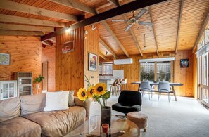 A cozy cabin interior with a wooden ceiling, a dining area, and a living room with a sofa and a coffee table. - Spacious | Pet Friendly| Near Boat Ramp and Water (Clifton Springs)