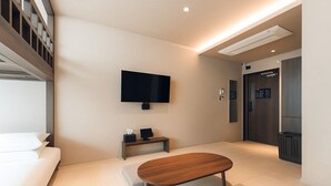 Una habitación de hotel moderna con una cama, un televisor en la pared, una mesita pequeña y un banco.
