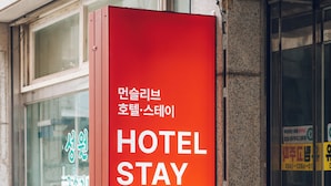 Un letrero rojo con la frase 'HOTEL STAY' y texto en coreano, que indica la ubicación de un hotel.
