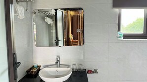A bathroom with a white sink, a mirror, and a window. - KST Linh Ky Moc (Quang Phu)