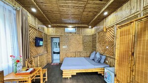 A room with a bed, a table with chairs, a small fridge, and a TV on the wall. - KST Linh Ky Moc (Quang Phu)