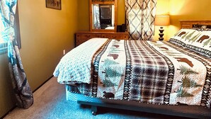 Een slaapkamer met een bed, een kroonluchter, een spiegel en een raam met gordijnen.