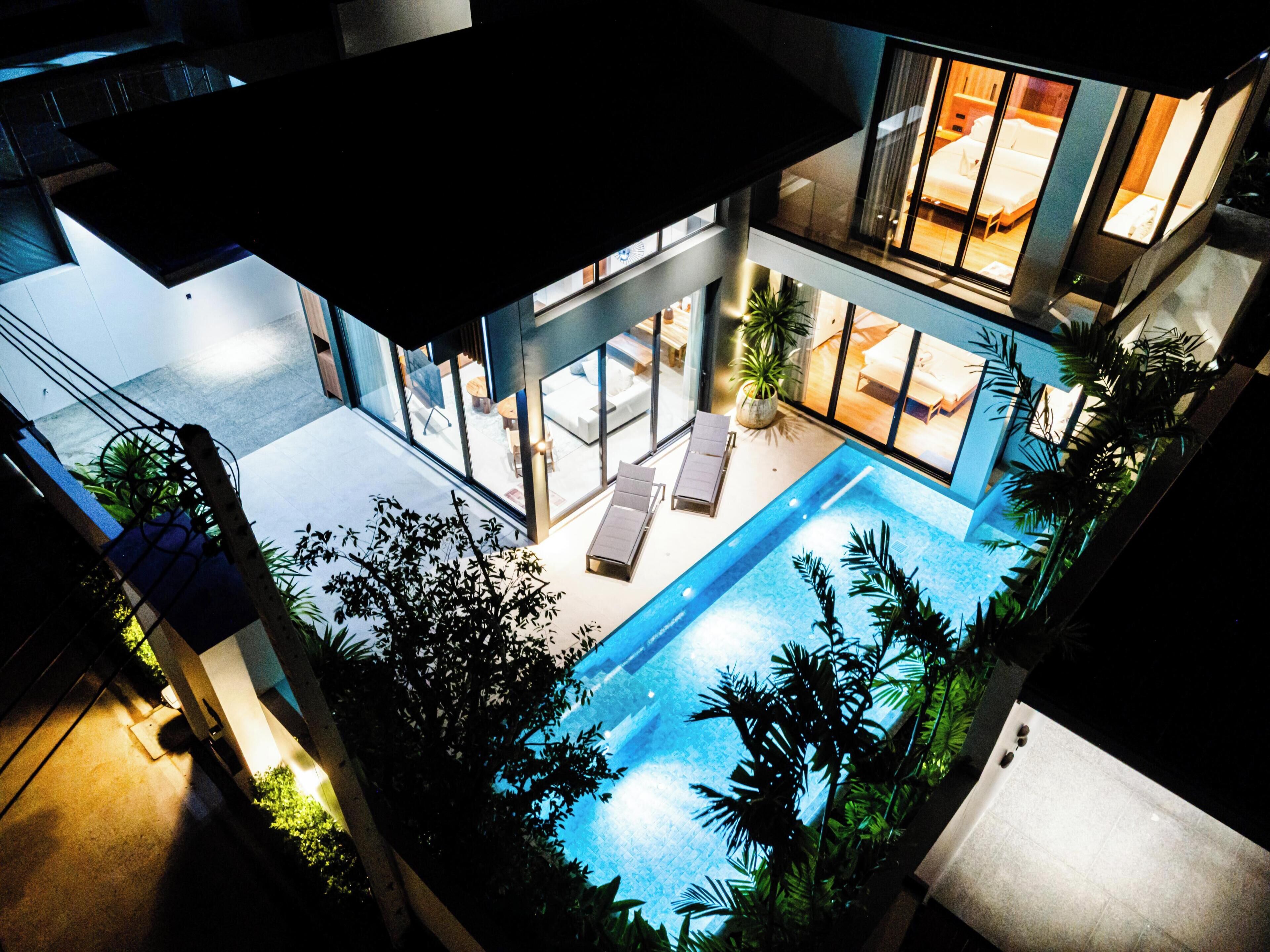 Un hotel moderno con piscina en la azotea, zona de estar al aire libre y amplias ventanas.