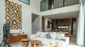 Un salón moderno con un sofá blanco, una mesa de centro de madera y un elemento decorativo en la pared.