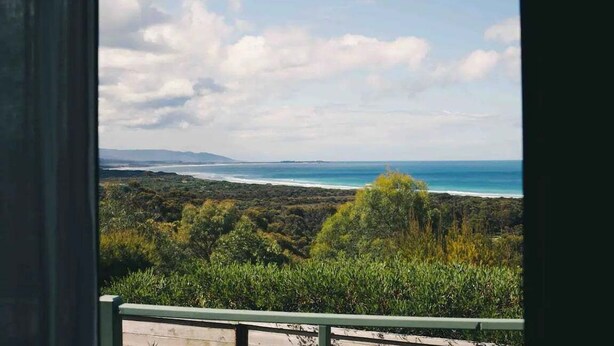 A coastal landscape with a view of the ocean and distant mountains. - Panorama Cabin - a cosy shack and an epic view (A) (Bicheno)