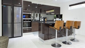 A modern kitchen with dark cabinets, stainless steel appliances, and a central island with bar stools.
