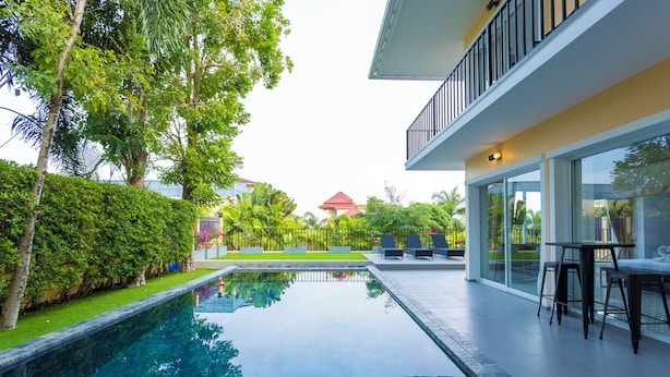 A modern pool area with a clear view of the pool, lounge chairs, and a dining area with tables and chairs.