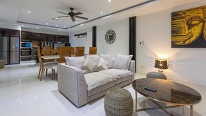 A modern living room with a sofa, coffee table, and dining area.