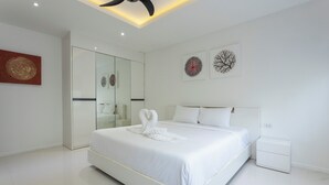 A modern bedroom with a large bed, a walk-in closet, and artwork on the walls.