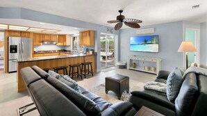 A modern kitchen with wooden cabinets, a central island, and a ceiling fan. - Sunny Marco Home with Heated Pool Near Beaches (Marco Island)