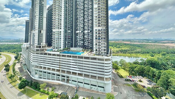 Un edificio residencial de gran altura con varios balcones, una piscina y un área de estacionamiento.