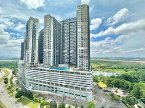 A high-rise residential building with multiple balconies, a swimming pool, and a parking area. - Afiniti Residences Medini by Stayrene (Iskandar Puteri)