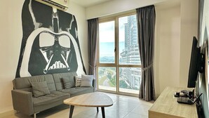 Una sala de estar moderna con un sofá gris, una mesa de centro redonda y un ventanal con cortinas.