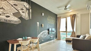 Una sala moderna con una pared temática de Star Wars, una zona de comedor con mesa y sillas, un sofá y un ventanal con cortinas.