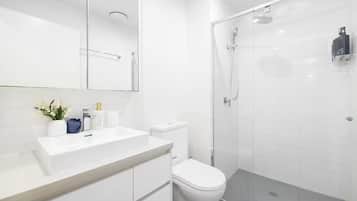 A modern bathroom with a white sink, toilet, and glass-enclosed shower.
